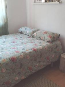 a bed with a floral comforter and two pillows on it at Casa rural El olivo in Puigmoreno