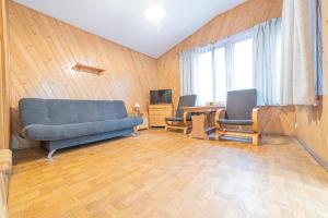uma sala de estar com um sofá azul e duas cadeiras em Ośrodek Wrzosowa Góra - domki em Ruciane-Nida