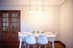 a white dining room table with four chairs and lights at Ideal Turismo Ribeira Sacra in Chantada