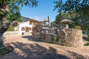 a house with a stone wall and a building at Sa Cova - Alcúdia in Alcudia