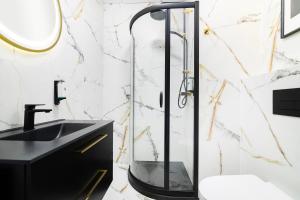 a glass shower in a bathroom with a black sink at Vola Palace in Warsaw +16 photos