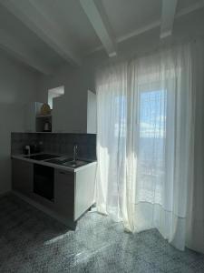 una cucina con lavandino e una finestra con tende di Casa Grazia Apartments a Città di Lipari