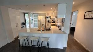 uma cozinha com um balcão branco e bancos em 1 - 5a Coochin Street, Dicky Beach - 200m To Beach em Caloundra