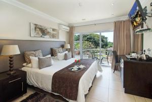 a bedroom with a bed and a desk and a window at uShaka Manor Guest House in Durban