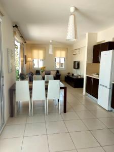 a kitchen and living room with a table and white chairs at Pyla Palms Resort B1 204 in Pyla