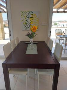 a dining room table with white chairs and a vase with flowers at Pyla Palms Resort B1 204 in Pyla