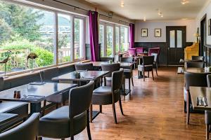 um restaurante com mesas, cadeiras e janelas em Loch Leven Hotel & Distillery em Glencoe