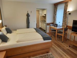 a bedroom with a bed and a desk and a kitchen at Appartementhaus Gaby in Bad Füssing
