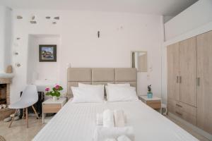 a white bedroom with a large bed and a chair at Ktima San Antonio Paros - Parion in Piso Livadi