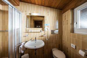 a bathroom with a sink and a toilet and a mirror at Hotel Waldheim in Sesto