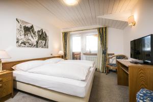 a bedroom with a white bed and a television at Hotel Waldheim in Sesto