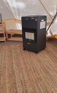 a heater is sitting in front of a tent at Glamping Žvaigždžių slėnyje 