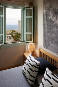 a bedroom with a window with a view of the ocean at Cycladic Villa ERoza in Ioulida