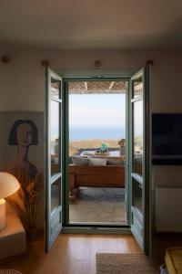 Habitación con una puerta corredera de cristal que conduce a una bañera. en Cycladic Villa ERoza, en Ioulida