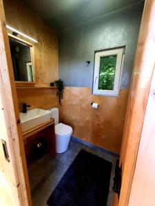 La salle de bains est pourvue d'un lavabo, de toilettes et d'une fenêtre. dans l'établissement Mazury Glamping, à Orzysz