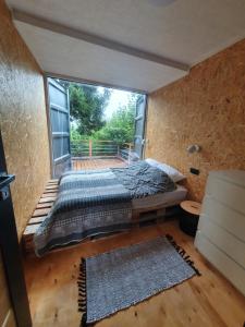 um quarto com uma cama e uma grande janela em Mazury Glamping em Orzysz
