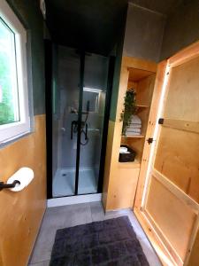 La salle de bains est pourvue d'une douche avec une porte en verre. dans l'établissement Mazury Glamping, à Orzysz