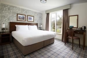 um quarto com uma cama, uma secretária e uma janela em The Swan at Grasmere- The Inn Collection Group em Grasmere