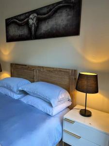 Una cama con almohadas azules y una lámpara en una mesita de noche en Earthy and Organic, en Johannesburgo