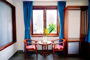 a table and two chairs in a room with a window at Villa Loan A HOI AN in Hoi An
