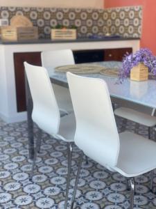 3 sedie bianche intorno a un tavolo in una sala da pranzo di Casa Grazia Apartments a Città di Lipari