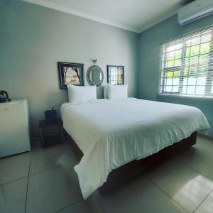 a bedroom with a large bed with white sheets at Twenty4ten Guesthouse in Gaborone