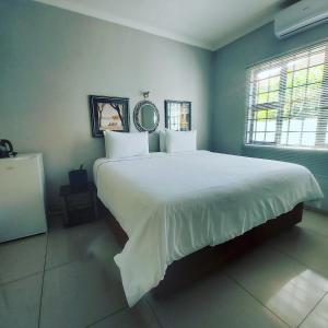 a bedroom with a large bed with white sheets at Twenty4ten Guesthouse in Gaborone +34 photos