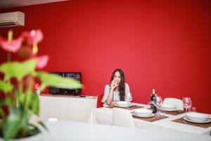 une femme assise à une table devant un mur rouge dans l'établissement Vieste holiday, à Vieste