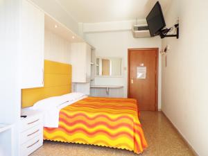 a bedroom with a yellow and white bed and a television at Hotel Crystal in Rimini