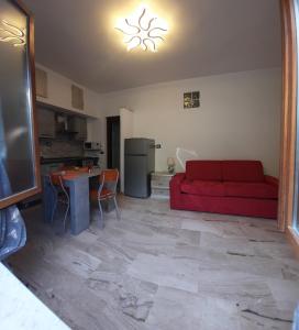 sala de estar con sofá rojo y cocina en Alba tra Monti e Mare, en Lanusei