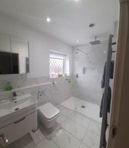 a white bathroom with a toilet and a sink at GOLF OPEN HOYLAKE Bungalow In West Kirby in West Kirby