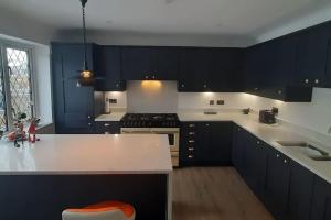 uma cozinha com armários pretos e um balcão branco em GOLF OPEN HOYLAKE Bungalow In West Kirby em West Kirby