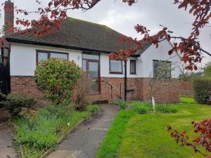 a white and red house with a yard at GOLF OPEN HOYLAKE Bungalow In West Kirby in West Kirby