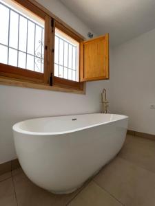 a large white bath tub in a bathroom with windows at Cortijo Avocado in Almuñécar +17 photos