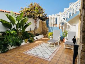 une terrasse avec des chaises blanches et des plantes dans une maison dans l'établissement La Dama del Mar, à Telde
