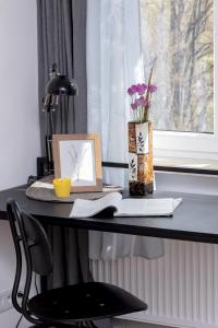a desk with a laptop and a book and a vase with flowers at Pet-Friendly Cosy Studio Skarbińskiego by Renters in Krakow