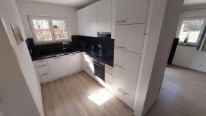 a kitchen with white cabinets and black counter tops at Ferienwohnung Claudia mit Terrasse in Nussdorf am Attersee