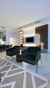 a living room with two green chairs and a television at Chalet 2200 in Al Khīrān