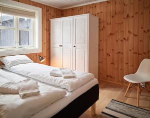 a bedroom with two beds and a cabinet and a chair at Stranda Fjellgrend in Stranda