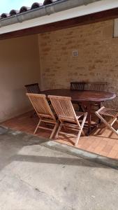 einen Holztisch und Stühle neben einer Ziegelwand in der Unterkunft Maison T4 a 6 minutes à pieds de Sarlat in Sarlat-la-Canéda