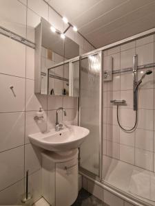 a white bathroom with a sink and a shower at Vier Jahreszeiten 4-29 in Großenbrode