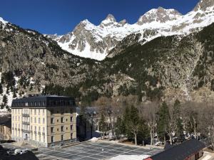 un edificio con montañas cubiertas de nieve en el fondo en Casa Pyrene - Acogedor apartamento familiar, en Sabiñánigo