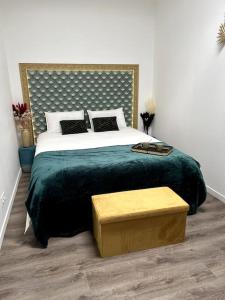 a bedroom with a large bed with a green blanket at La suite, avec jacuzzi & sauna in Muret