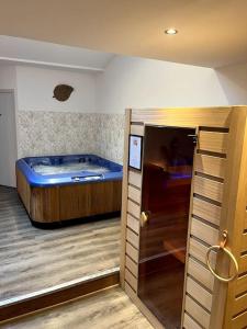 a room with a tub in a room with a door at La suite, avec jacuzzi & sauna in Muret
