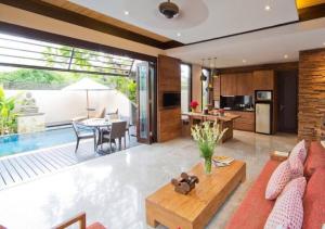 a living room with a couch and a table and a kitchen at Villa Canthy@Seminyak in Seminyak