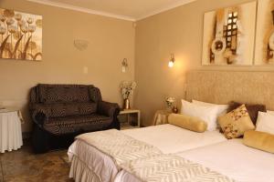 una habitación de hotel con 2 camas y una silla en Villa Ticino Guest House en Sabie