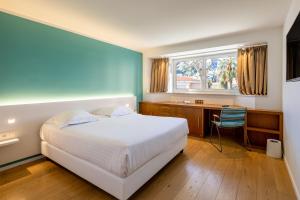 a bedroom with a bed and a desk and a window at Hôtel Riva Art & Spa in Menton