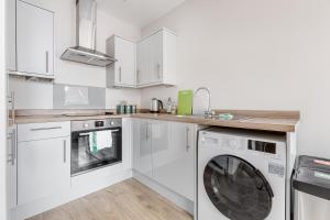 a white kitchen with a washing machine in it at Modern Apt, town centre, 4 guests, pkg, wifi by Tent serviced apartments in Farnborough