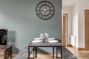 a dining room with a table with glasses and a clock at Modern Apt, town centre, 4 guests, pkg, wifi by Tent serviced apartments in Farnborough