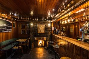 a bar with a fireplace and a table and chairs at Loch Leven Hotel & Distillery in Glencoe